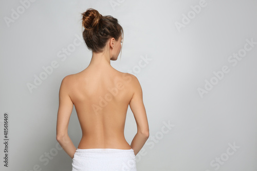 Back view of woman with perfect smooth skin on light grey background, space for text. Beauty and body care