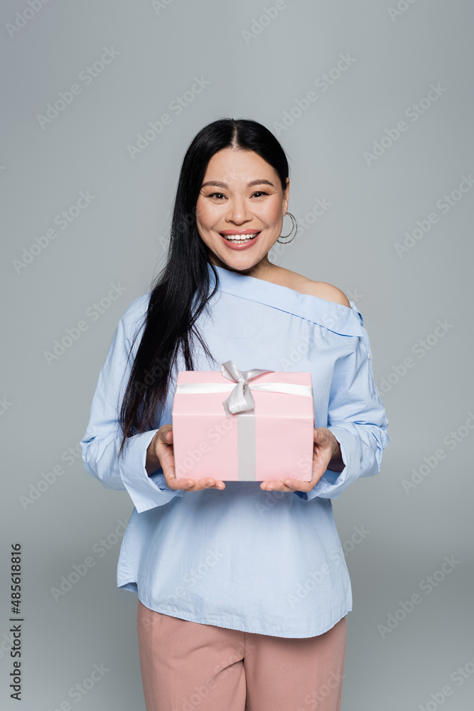 Joyful asian woman holding present isolated on grey Joyful asian woman holding present isolated on grey