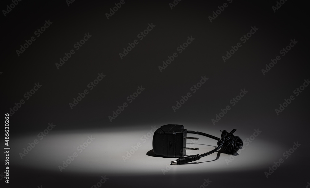 High to low voltage electrical charger device for American power outlets in a beam of light on dark background