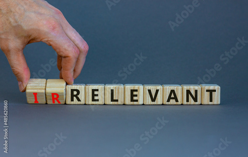 Relevant or irrelevant symbol. Businessman turns wooden cubes changes the word irrelevant to relevant. Beautiful grey table grey background. Business, relevant or irrelevant concept. Copy space. photo