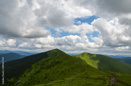 Summer landscape with green mountain slopes covered clouds shadows in Ukrainian Carpathians. Travel and adventure concept