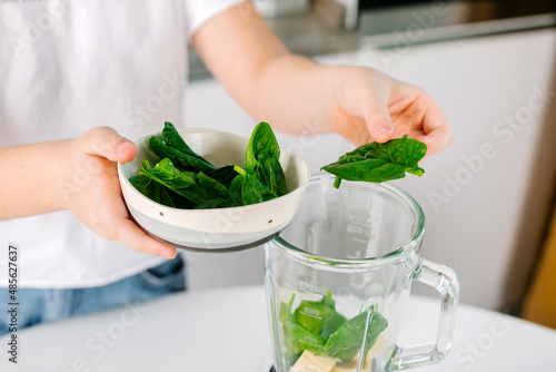 Woman putting raw ingredients into a blender to make fresh homemade smoothie