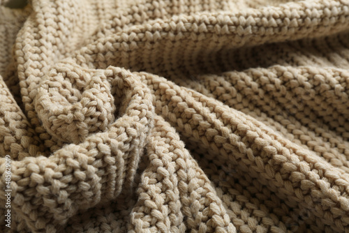 Beautiful beige knitted fabric as background, closeup