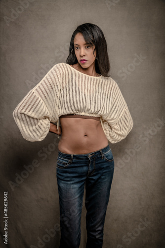 Tall and Glamorous BIPOC woman with long hair poses in a Los Angeles studio in jeans and a cropped sweater. photo