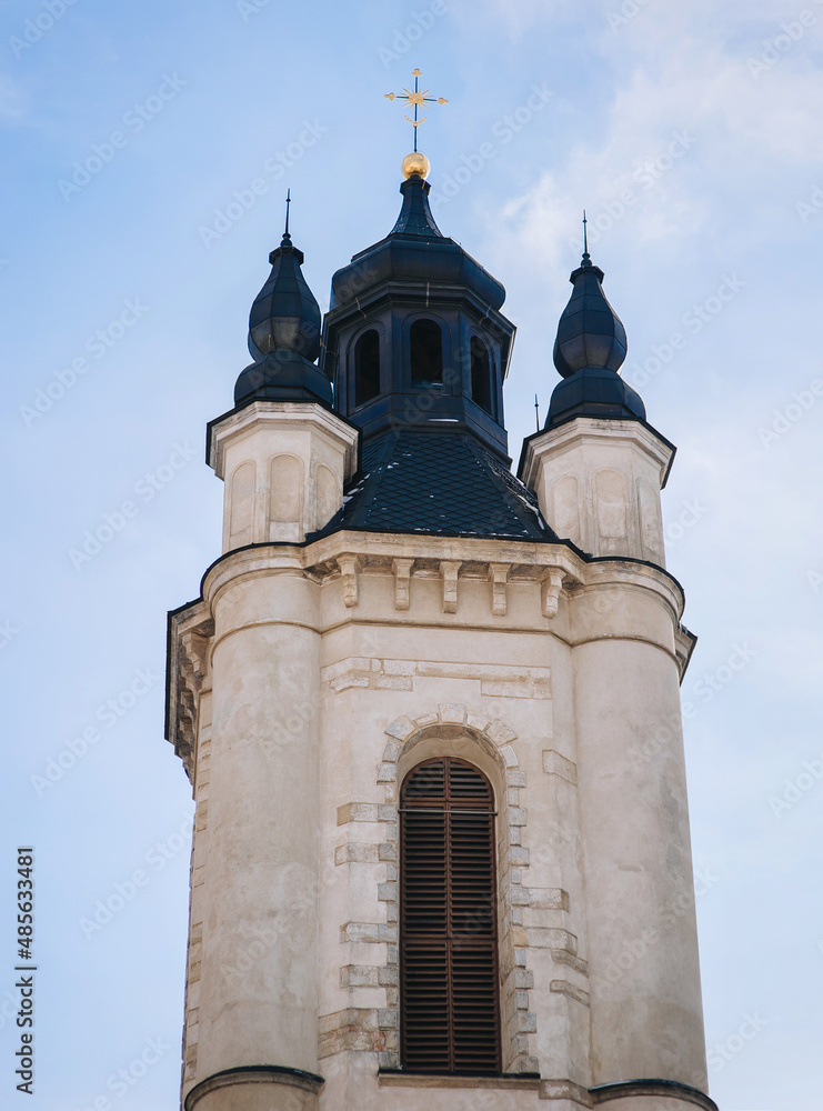 Old stone Armenian church in the form of a light tower with cross against the blue sky. Lviv, Ukraine.