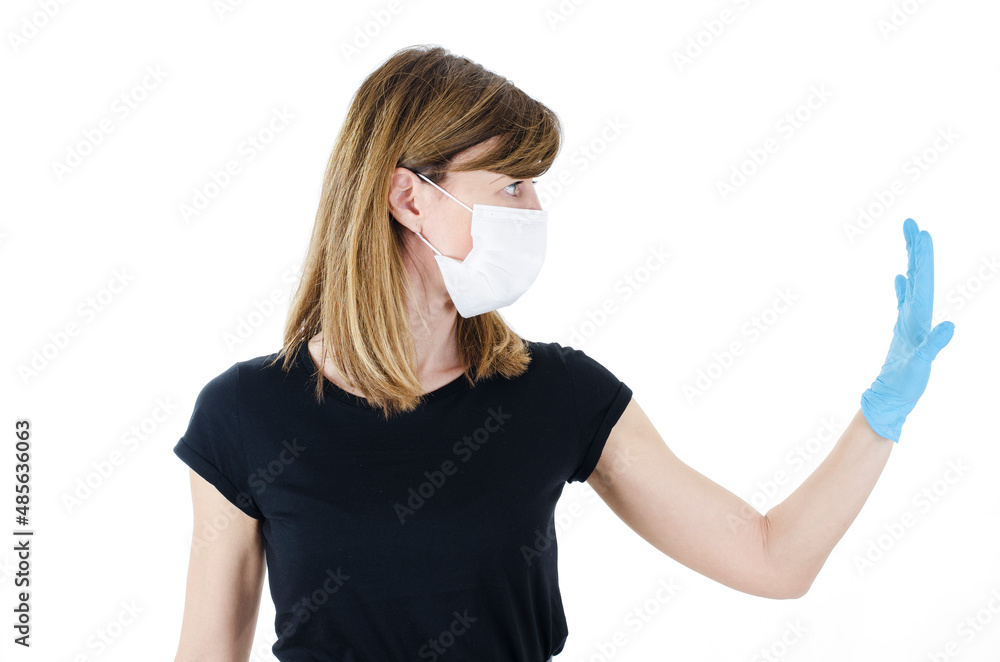 Woman social distancing from corona virus covid-19 wearing a protective white face mask and medical gloves holding up hand saying stop. Isolated on white background. Side view of young woman. Woman social distancing from corona virus covid-19 wearing a protective white face mask and medical gloves holding up hand saying stop. Isolated on white background. Side view of young woman.