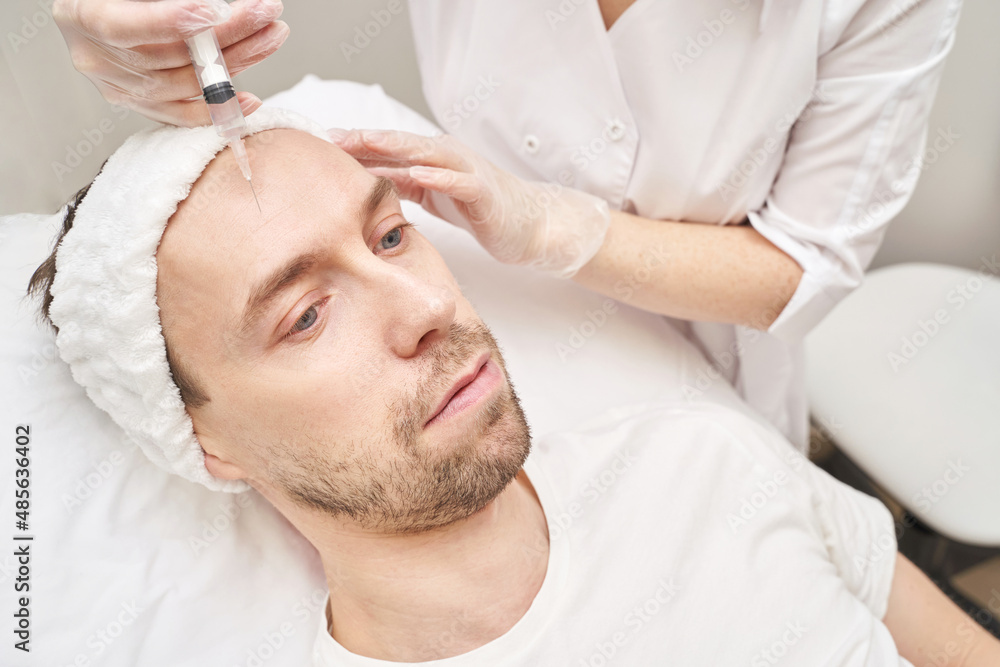 Obraz premium Injection at spa salon. Doctor hands in gloves. Closeup. Pretty male patient. Beauty treatment. Healthy skin procedure. Young man face. Plasmolifting rejuvenation