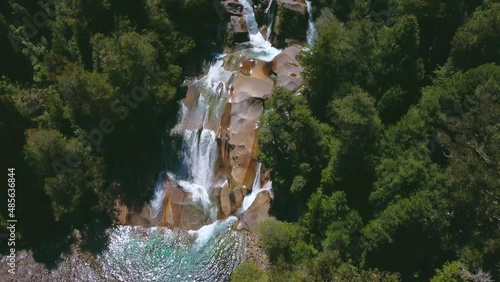 Toma aérea de cascadas naturales pasando por rocas en medio de bosques.