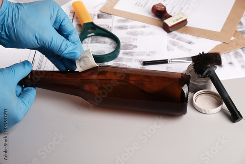 Forensic fingerprint analysis, criminalist collects latent fingerprints using fingerprint powder on evidence photo