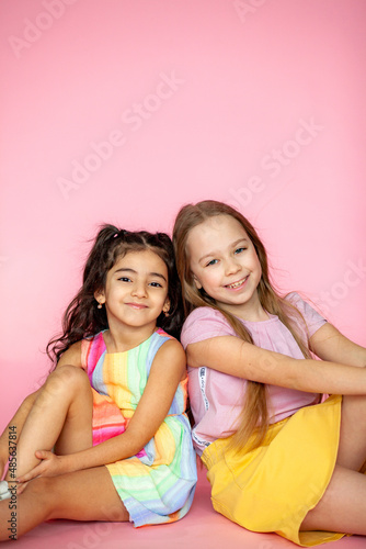 Funny little girls 7-10 years old in casual summer clothes posing on a solid pink background. The concept of a child's lifestyle. Layout of the copy space.