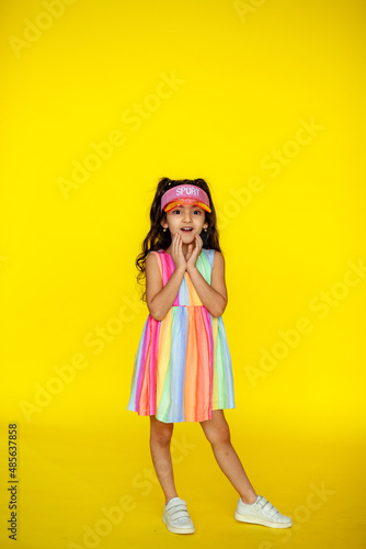 Funny little girl about 6 years old in casual summer clothes posing on a plain yellow background. The concept of a child's lifestyle. Layout of the copy space. © Нина Зайцева