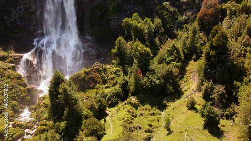 Waterfall and river in green meadow and forest.
