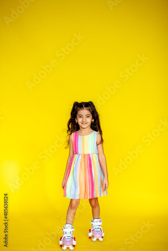 Funny little girl about 6 years old in casual summer clothes posing on a plain yellow background. The concept of a child's lifestyle. Layout of the copy space.