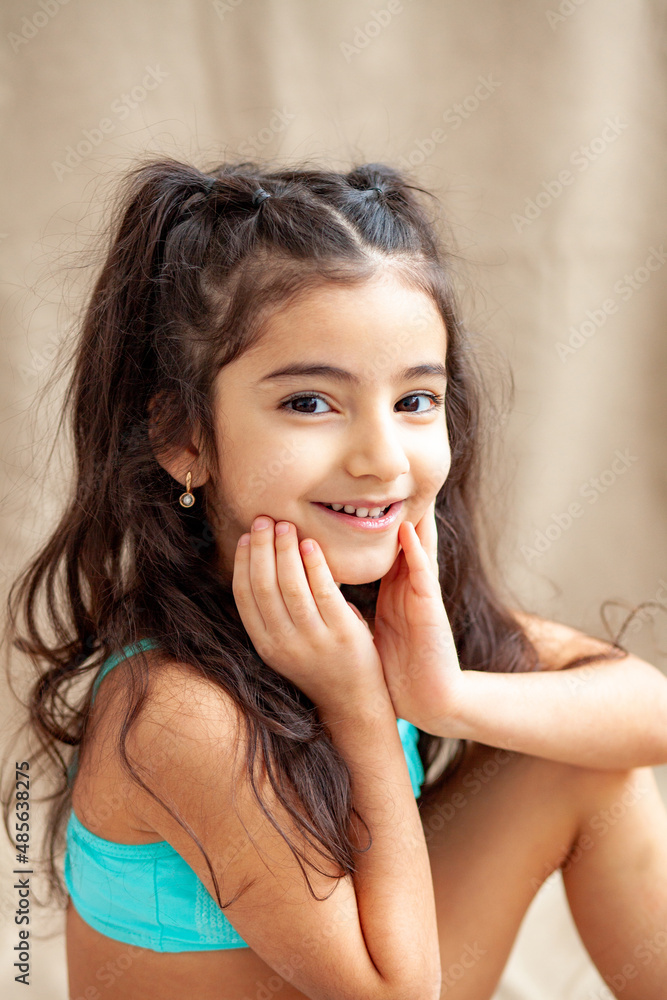 Funny little girl about 6 years old in a casual summer swimsuit posing on a plain beige background. The concept of a child's lifestyle. Layout of the copy space. Funny little girl about 6 years old in a casual summer swimsuit posing on a plain beige background. The concept of a child's lifestyle. Layout of the copy space.
