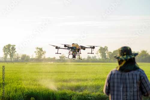 Young smart farmer controlling drone spraying fertilizer and pesticide over farmland,High technology innovations and smart farming