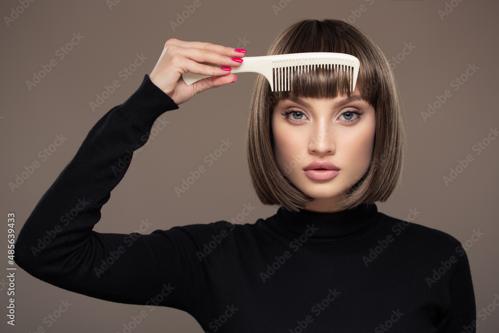 Obraz premium Portrait of a beautiful woman with a short haircut holding a comb in her hand.