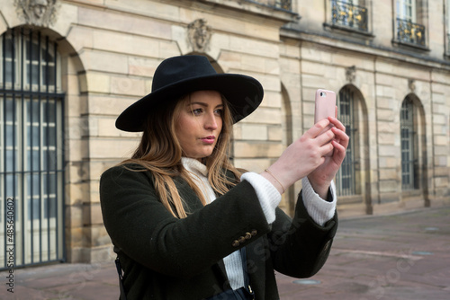 Portrait of young woman taking a photo with her smartphone in the street