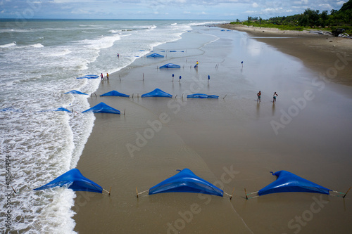 Dhaka, Bangladesh - 28 August 2021: Aerial view of people setting fishing nets along the shoreline on the beach in Bangladesh. photo