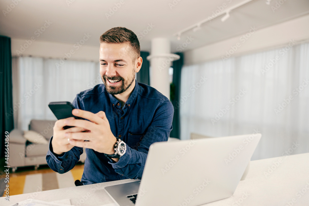 A happy man sending a message at home. A happy man sending a message at home.