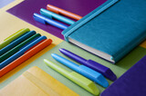 Bright notepads and colored pens on a background of colored paper. writing accessories. Corporate gifts for office employees. Sunny mood for work.