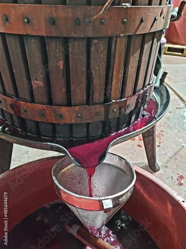 Bild auf Leinwand Fermented wooden wine grape press with wine juice pouring over stainer