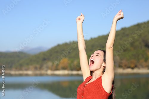 Euphoric woman celebrating raising arms in summer