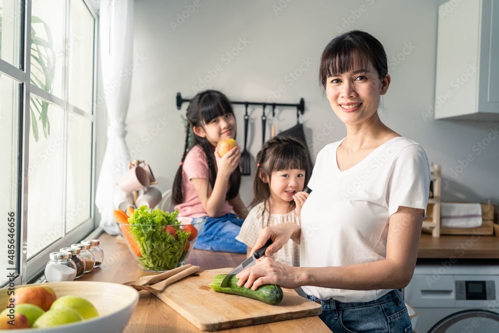 Asian lovely mother cooking breakfast with young daughter in kitchen. 