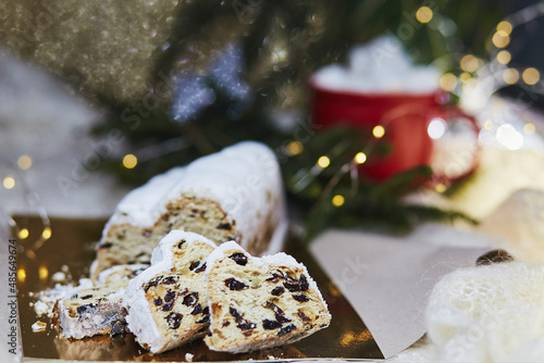 Festive Christmas stollen, Christstollen - classic Christmas yeast bread. Hot beverage with marshmallow. Cozy aesthetic dinner. Christmas tradition with bokeh background. Festive background.