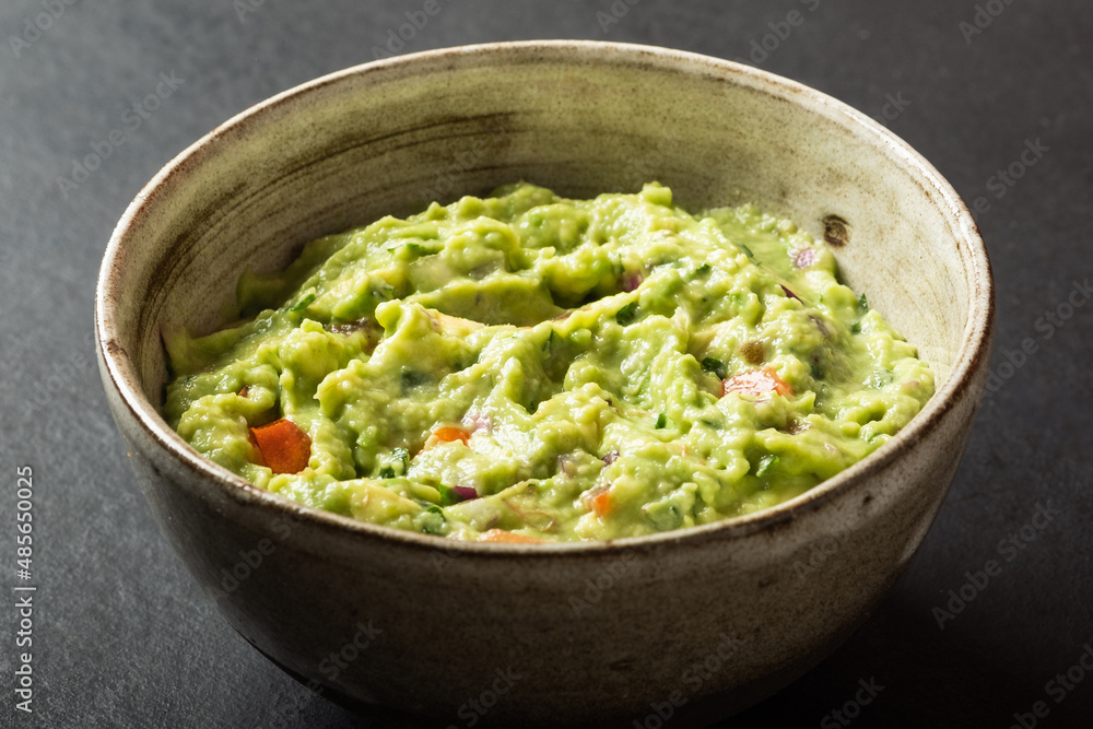 Traditional Mexican Guacamole sauce made from avocado. lime, red onion, tomatoes, cilantro on a pink background. Traditional Mexican Guacamole sauce made from avocado. lime, red onion, tomatoes, cilantro on a pink background.