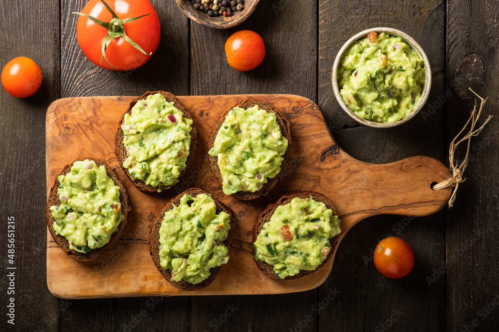 Sandwiches with guacamole sauce on a cutting board over old wooden background. Sandwiches with guacamole sauce on a cutting board over old wooden background.