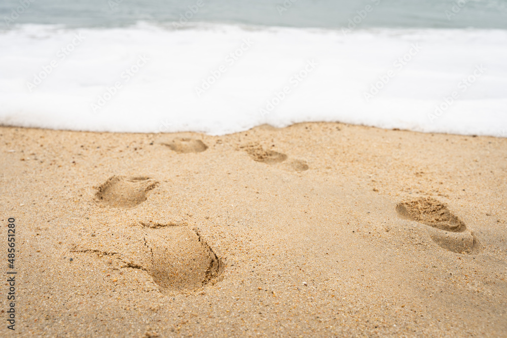 Close up on footprints on sand at beach seashore. Loneliness by the sea concept Close up on footprints on sand at beach seashore. Loneliness by the sea concept