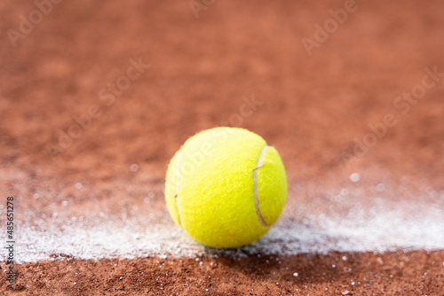 Tennis ball on white line on clay court close up. Sports tournament competition, in or out concepts © Josu Ozkaritz