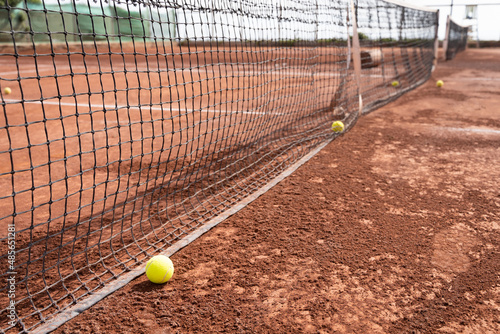 Tennis balls by net on clay court. Sports tournament, training concepts © Josu Ozkaritz