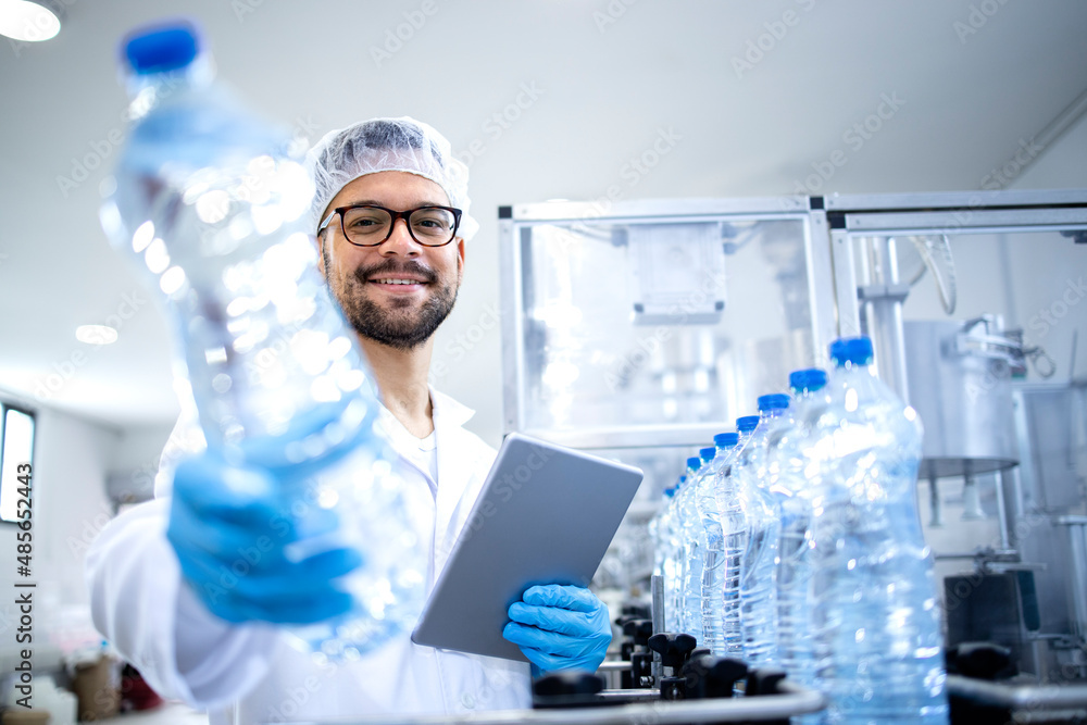 Fototapeta premium Working in bottling water factory and production line worker checking quality of beverage and plastic packaging.