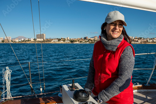 Adult Woman steering yacht on the bay of Alicante, Costa Blanca, Spain