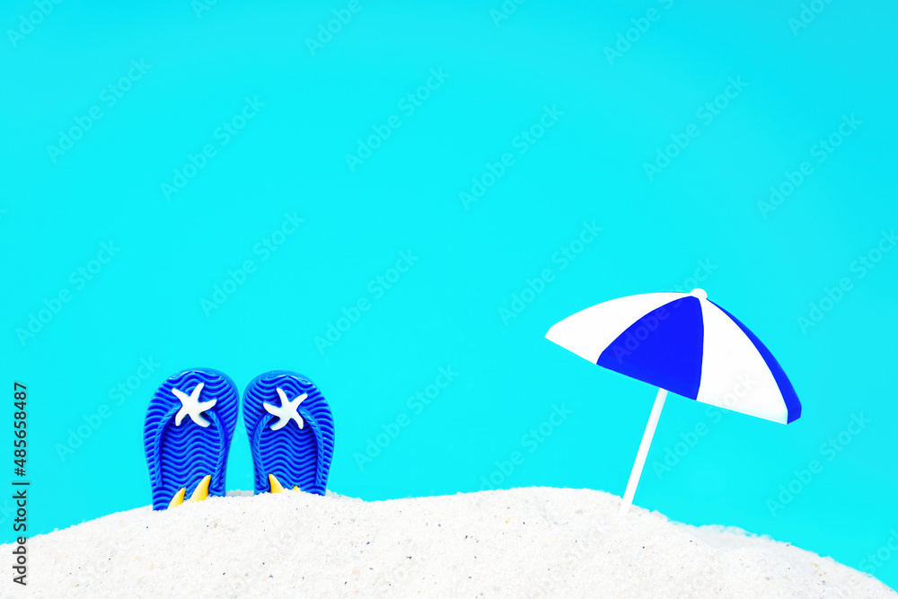Blue flip flops and sun umbrella in sand Blue flip flops and sun umbrella in sand