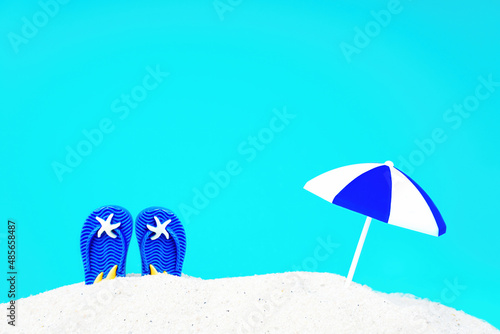 Blue flip flops and sun umbrella in sand