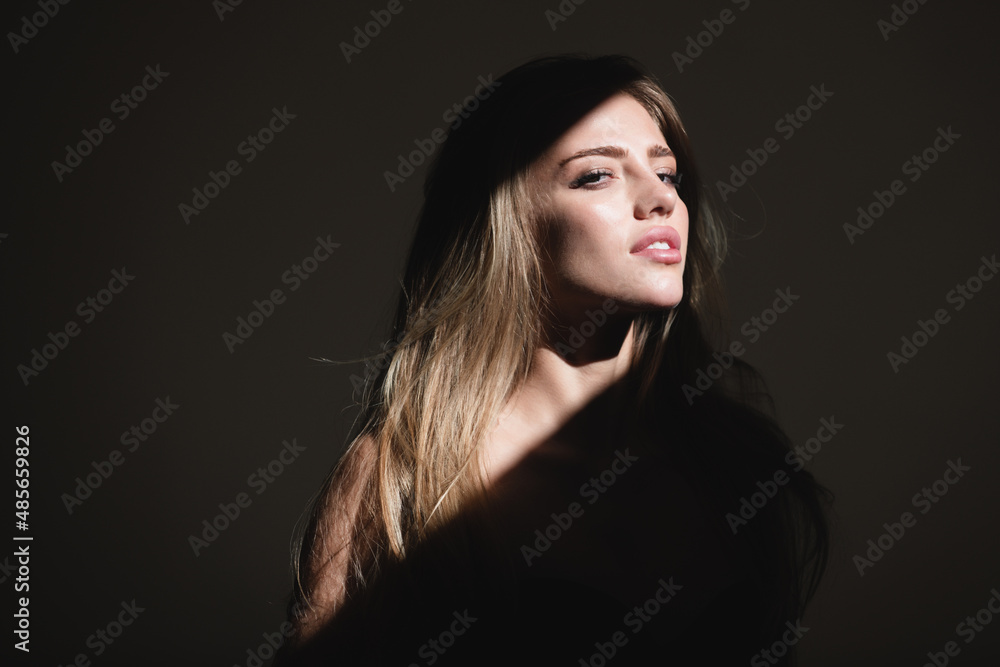 Sensual girl. Portrait of elegant woman with light on a black background. Beautiful female face in the darkness.