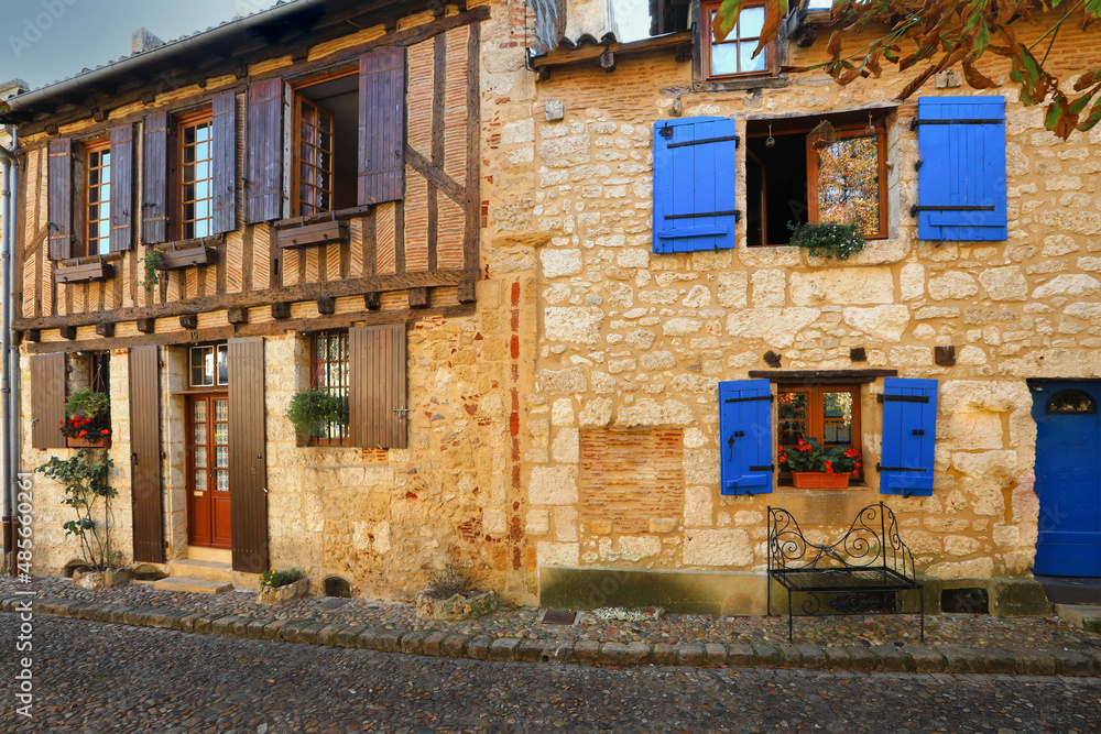 Facade of stone houses with wooden doors and blue windows in Bergerac town, France