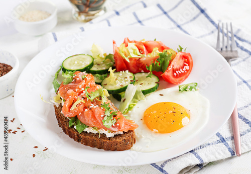Diet breakfast. Fried eggs and sandwiches with salt salmon and cucumber, tomatoes, lettuce.