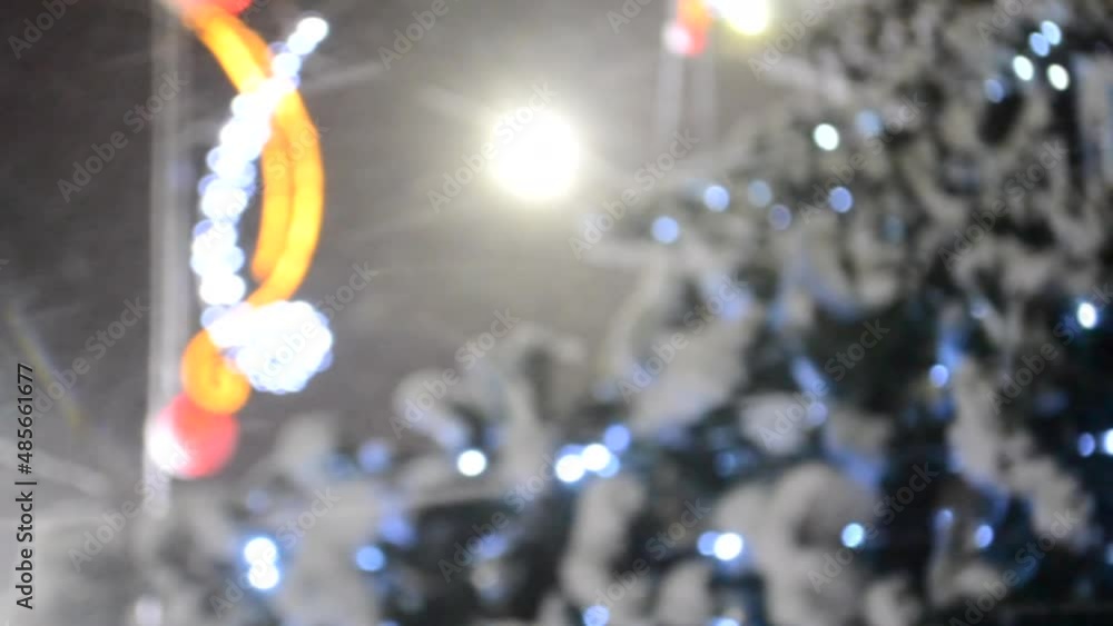 Christmas tree covered snow, glowing colorful lights during snowfall outdoors. Abstract Christmas New Year background. Blurred snowy winter background. Light twinkling. Vertical video Seamless looping Christmas tree covered snow, glowing colorful lights during snowfall outdoors. Abstract Christmas New Year background. Blurred snowy winter background. Light twinkling. Vertical video Seamless looping