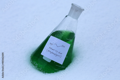 Green ethylene glycol in a conical flask on the snow. The main raw material for the production of coolants. photo
