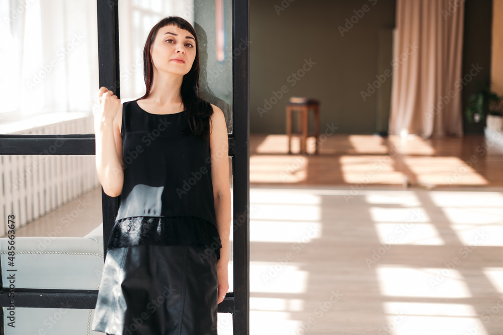 Portrait of a beautiful calm brunette woman in a large sunny room.