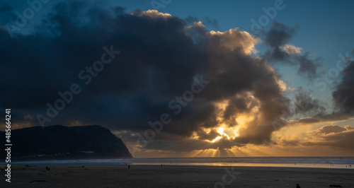 A panorama image of a sun burst at sunset and Tillamook Head headland and the beach at Seaside Oregon.