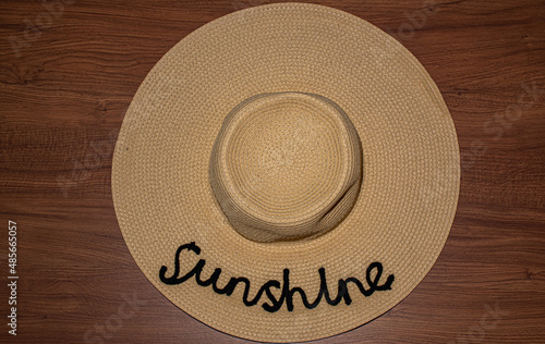 chapéu sobre a madeira com aba larga com a palavra sunshine bordada