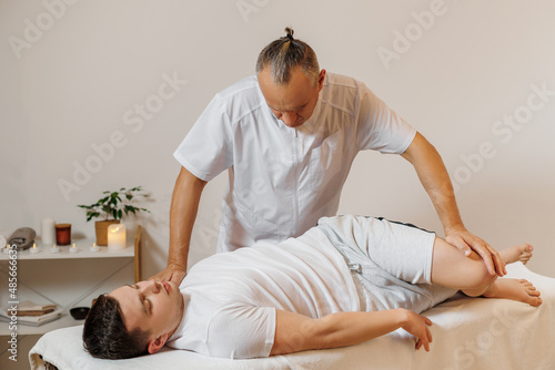 Strong and concentrated masseur therapist in uniform making manual therapy for sportsman. Professional massage back treatment. Back muscle stretching. Concept of wellness, body and health care.