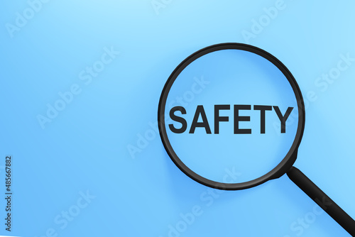 On a blue background, a magnifying glass with the text SAFETY. Business concept