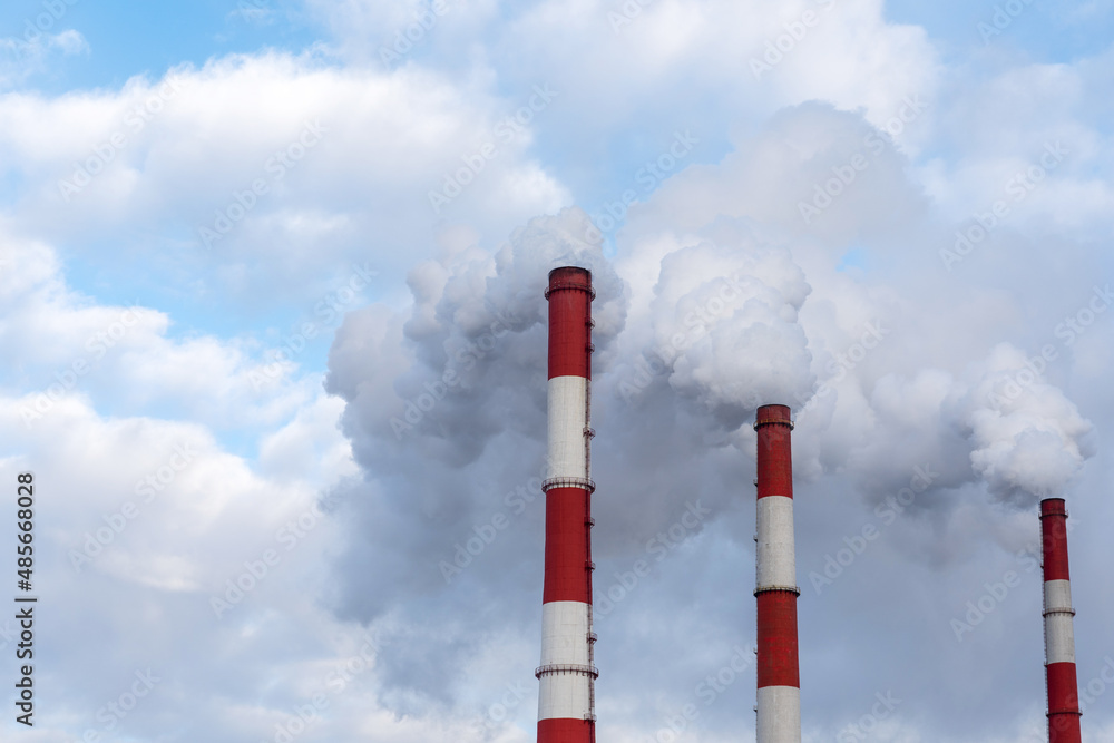 three chimneys with a lot of steam and smoke against a blue clear sky three chimneys with a lot of steam and smoke against a blue clear sky