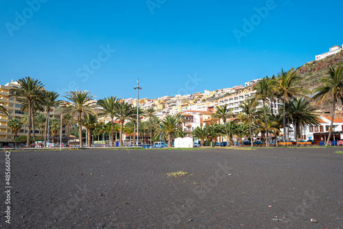 Promenade and black sand beach of San Sebastian de La Gomera, the capital of the Canary Island of Gomera. The colorful houses stretch from the hill down to the sea © ksl