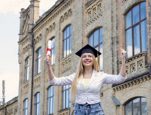 Happy young woman student in a graduation hat on the background of the university. Completion of studies and diploma of education. © A Stock Studio